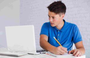 How to Prepare for Final GCSE Exams in Year 11 — Step-by-Step A focused teenage boy using a laptop and notebook for virtual study and effective online revision in preparation for GCSE Exams in Year 11.