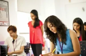 Best Online Training for English Language Success in Pakistan Four students sitting in a library, each holding and reading a book attentively.